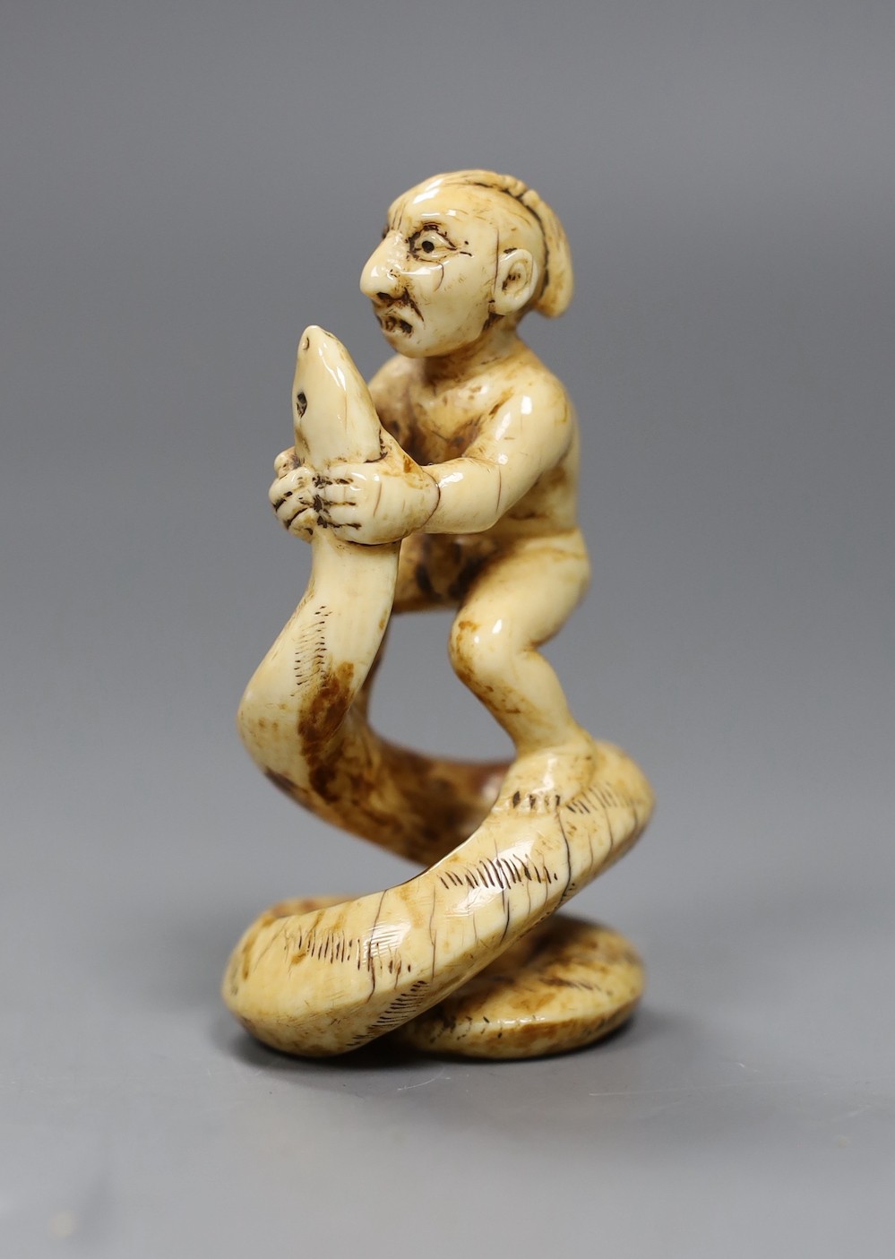 A 19th century native American marine ivory group of a warrior wrestling a snake, 7cm high
